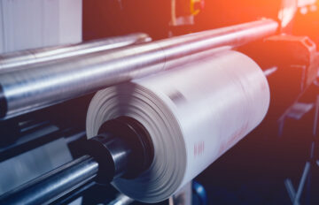 Рулон поліетиленової плівки на валу екструдера в цеху